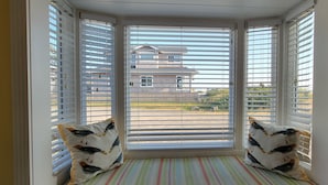 A room with a bay window, striped floor, and two pillows with bird designs. - Sea Sprite at Haystack Rock (Cannon Beach)