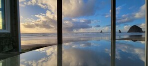 A beach view through a window with a clear sky and calm sea.