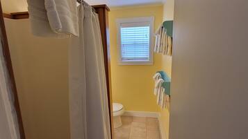 A bathroom with a shower curtain, a toilet, and towels hanging on a rack.