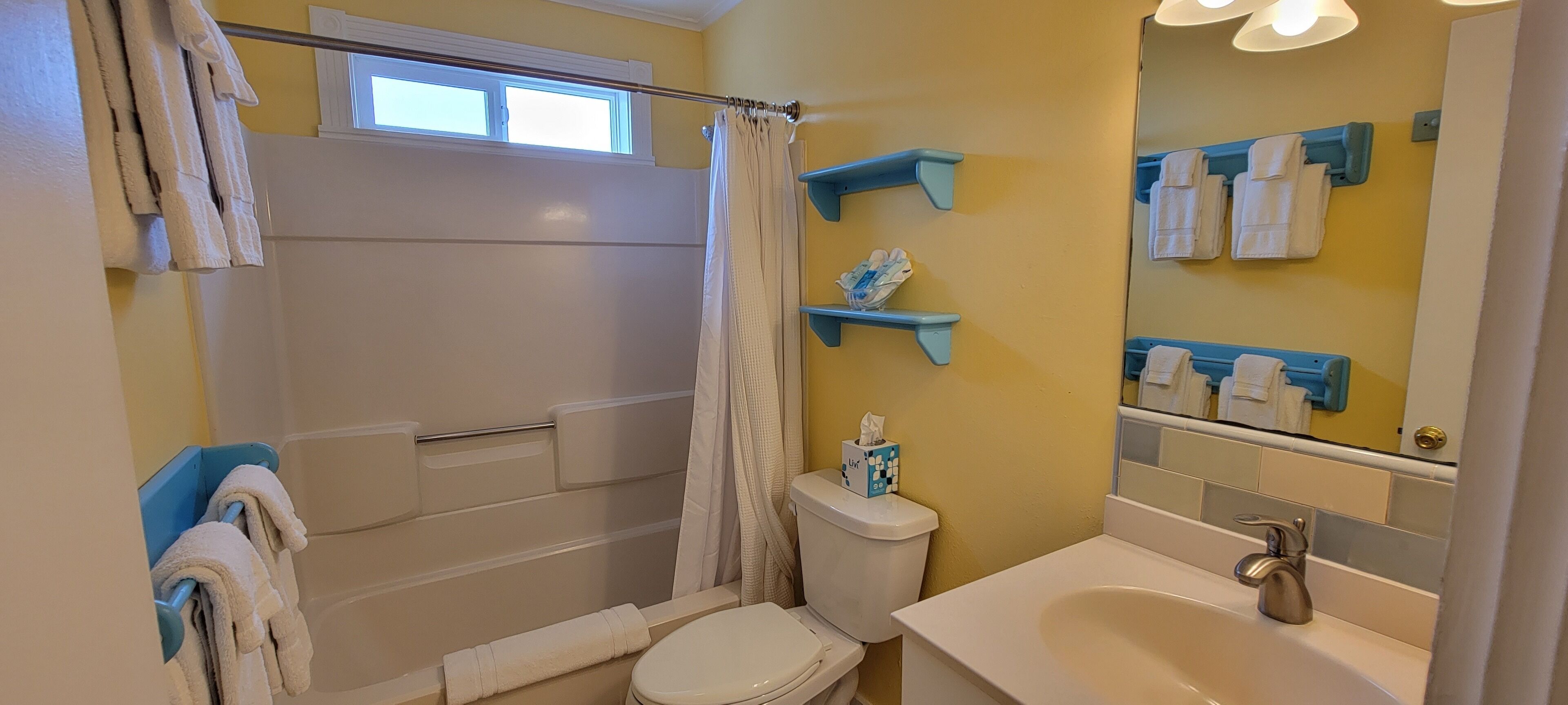 Une salle de bain équipée d’une douche, de toilettes, d’un lavabo et de porte-serviettes.