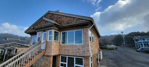 A two-story wooden house with a balcony and a staircase leading to the second floor.