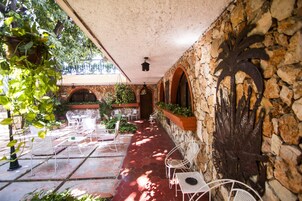 Un patio al aire libre con muros de piedra, arcos y plantas colgantes.