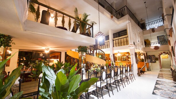 A spacious hotel lobby with a high ceiling, multiple dining areas, and a staircase connecting different levels. - Ideal Villa Hotel (Port-au-Prince)