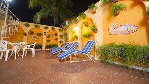 A terrace with lounge chairs, a staircase, and a mural of a fish. - Ideal Villa Hotel (Port-au-Prince)