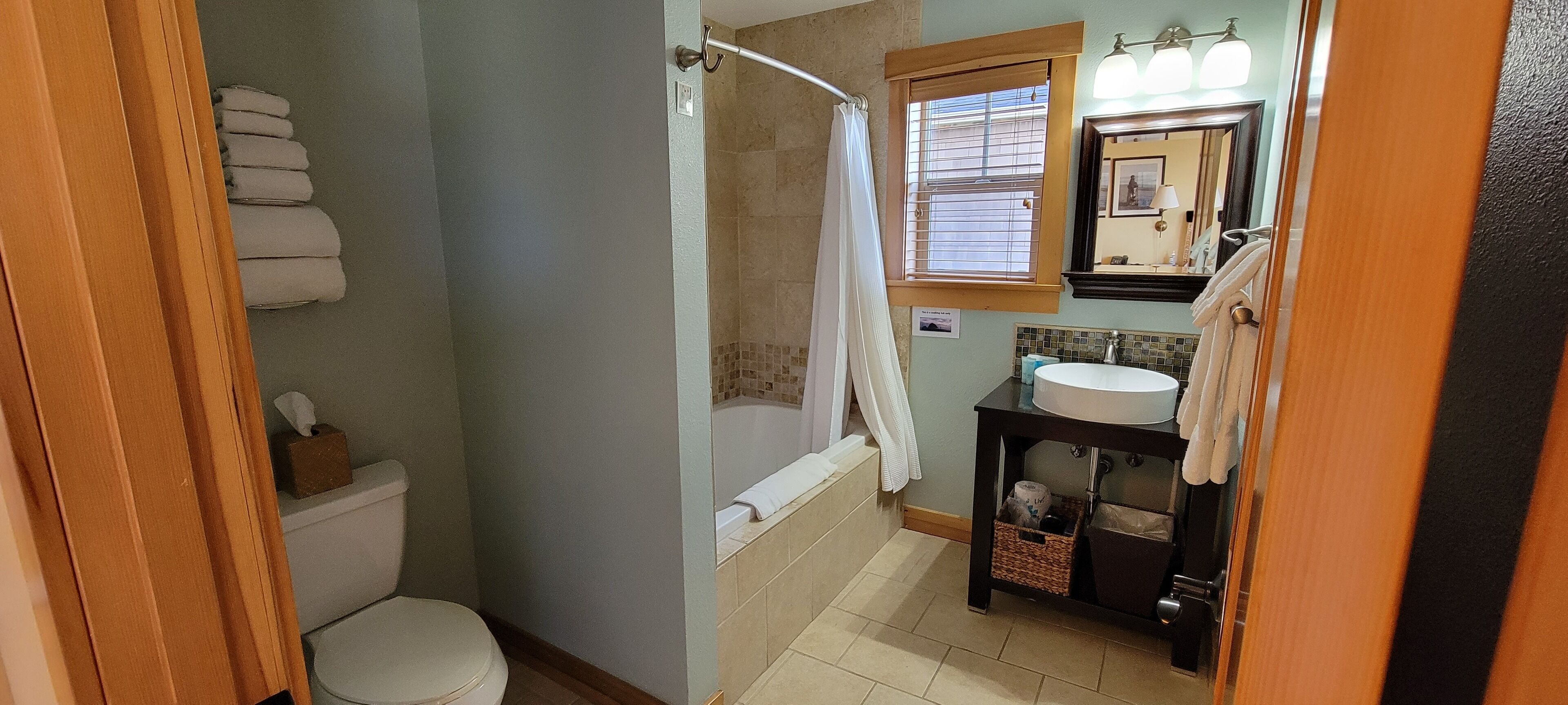 A bathroom with a toilet, a bathtub, a sink, and a mirror.