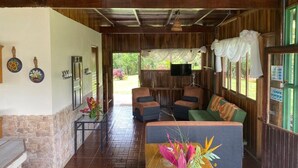 A cozy room with a wooden ceiling, a sofa, a table with a vase of flowers, and a television on a wooden stand. - Villas Josipek (Peñas Blancas)