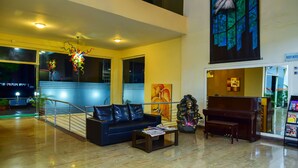 A spacious lobby with a blue sofa, a piano, and a Buddha statue. - Inventree Hotel, Hinjewadi (Paud)