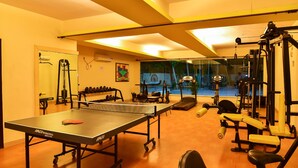 A gym with a ping pong table, weight machines, and a treadmill. - Inventree Hotel, Hinjewadi (Paud)