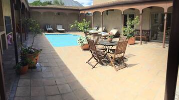 A covered outdoor area with a pool, seating, and potted plants.