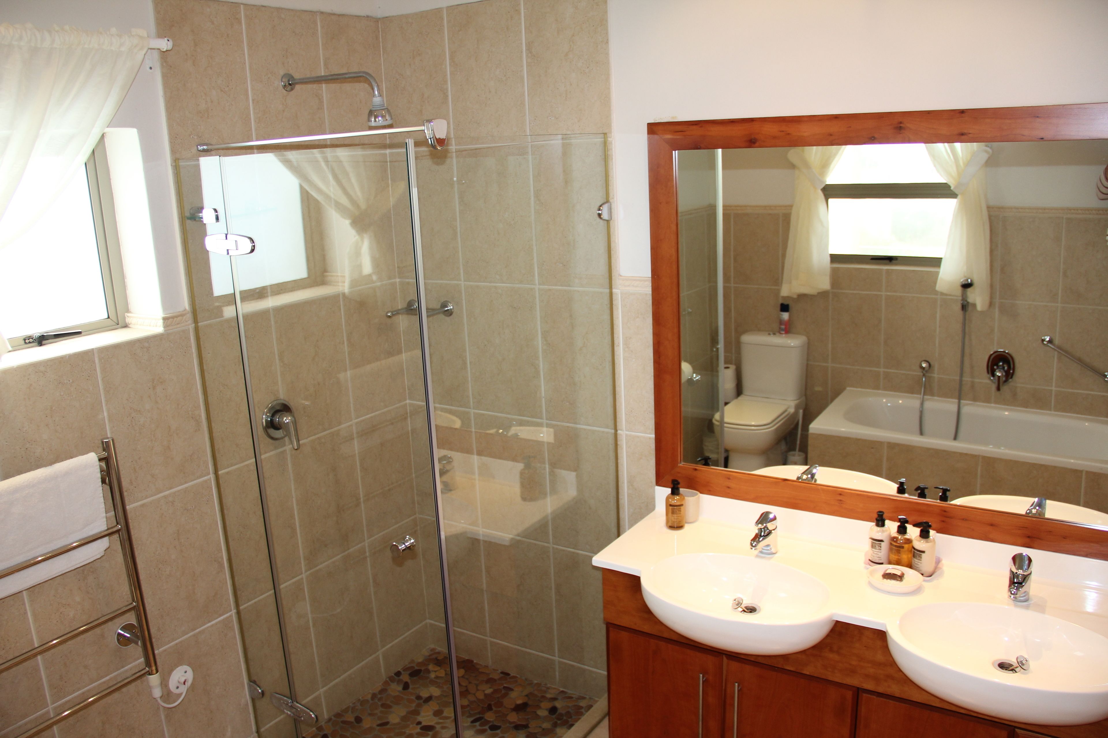 A bathroom with a glass shower enclosure, two sinks, and a large mirror.