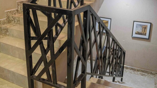 A staircase with a metal railing, leading to a landing area with a picture on the wall. - Bridgeview Hotel & Conference Centre (Lilongwe)