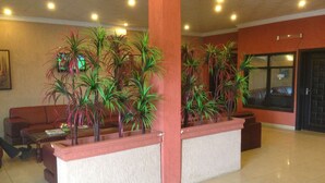 A lobby with a reception desk, several potted plants, a brown leather sofa, and a tiled floor. - Bridgeview Hotel & Conference Centre (Lilongwe)