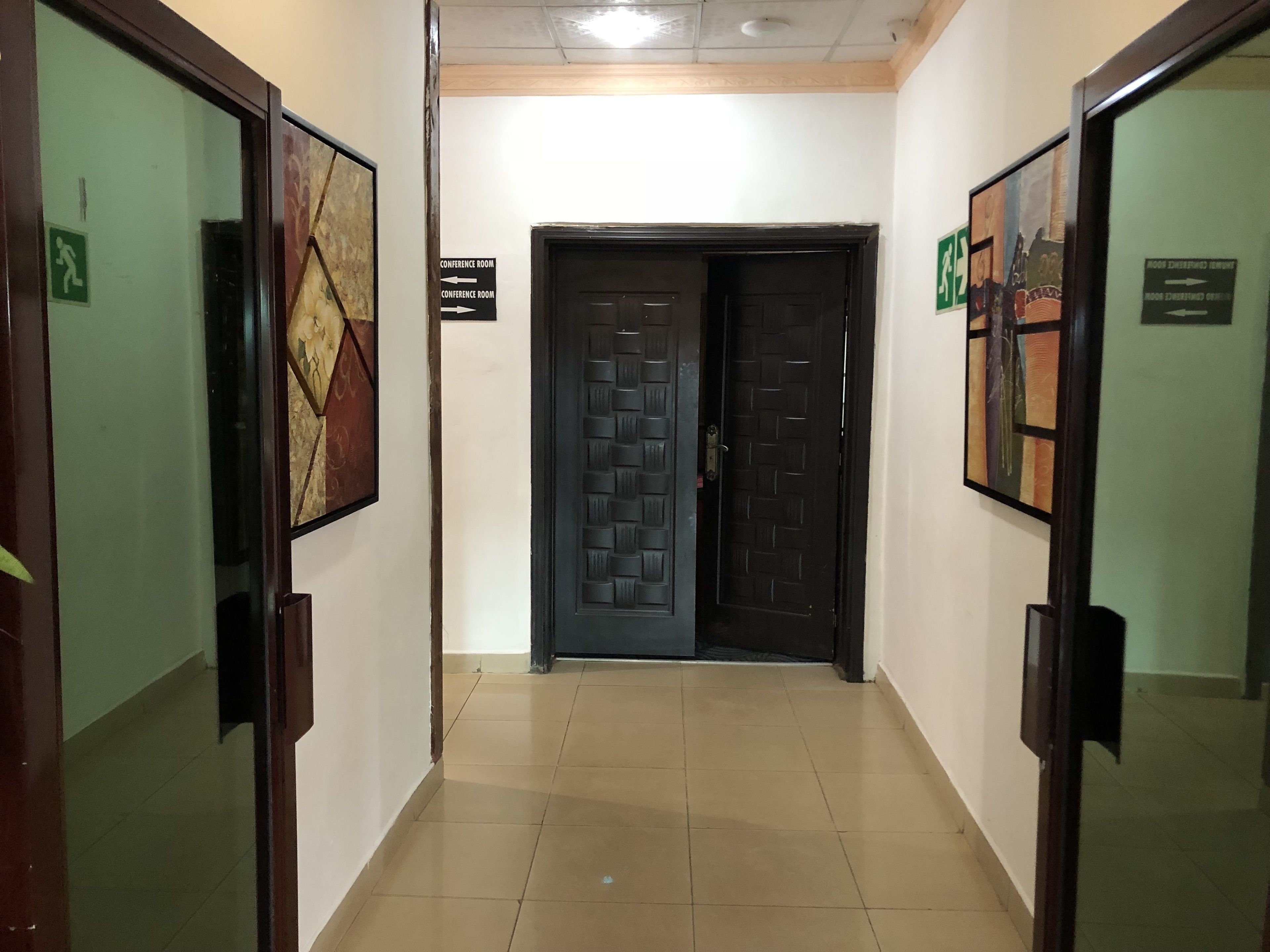 A hallway with two doors, each with a framed picture above. There are signs indicating a conference room and a room for children.