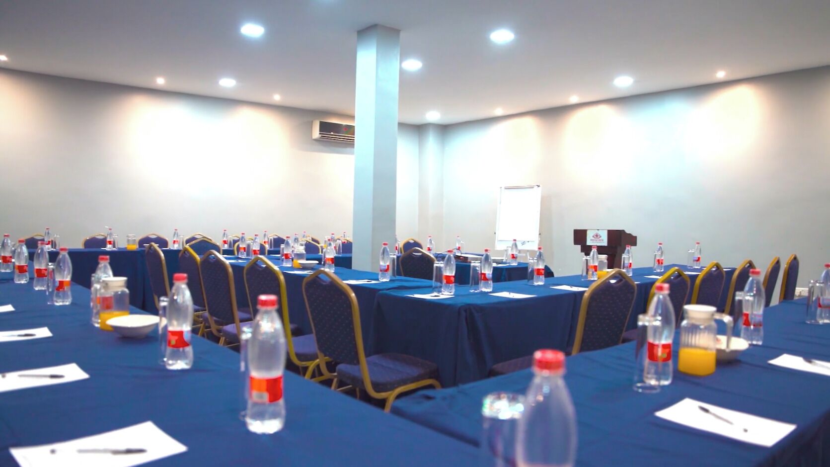 A conference room with tables set up for meetings, equipped with water bottles and notepads.