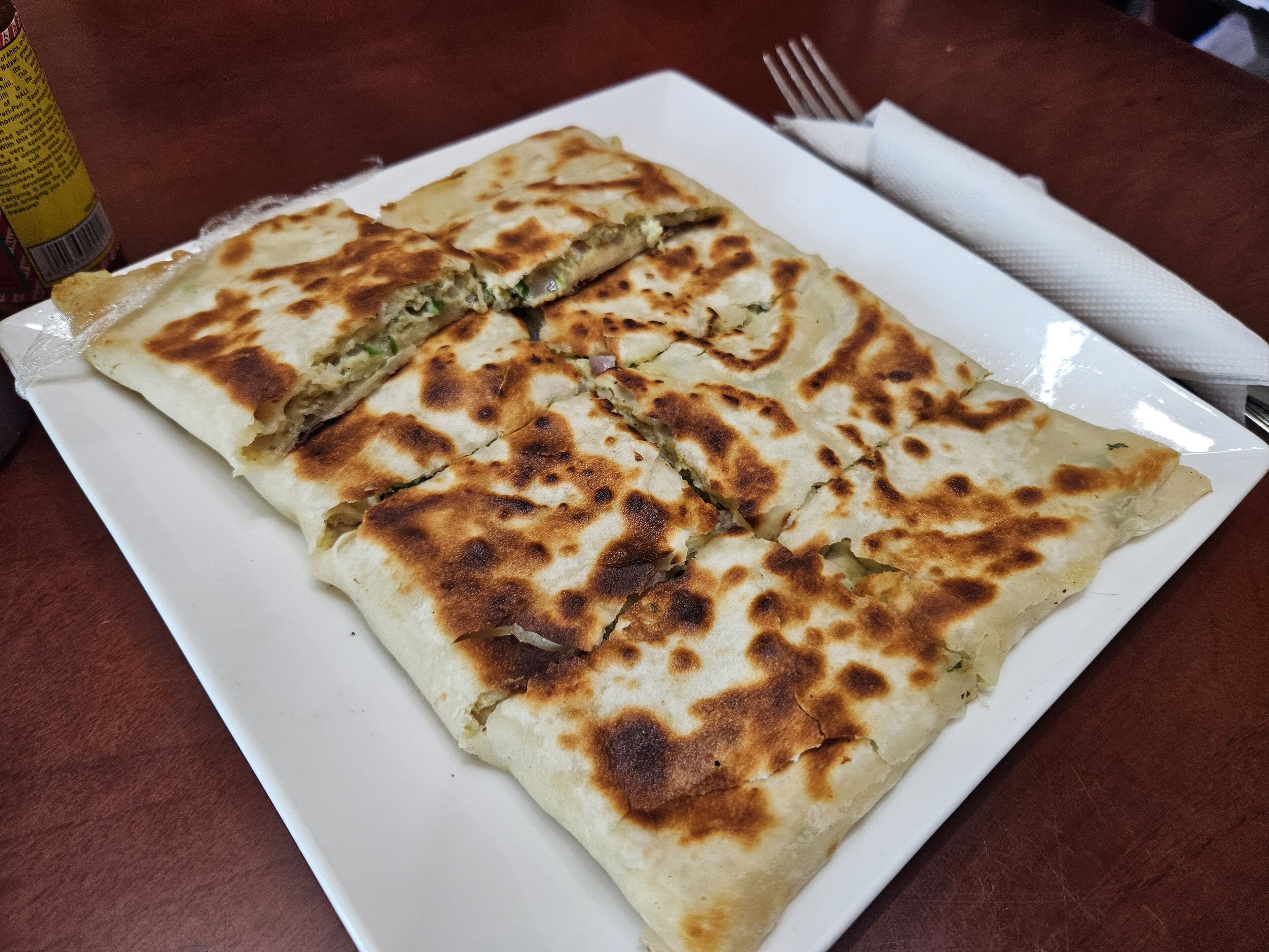 Ein Teller Fladenbrot mit goldbrauner Kruste, in Stücke geschnitten.