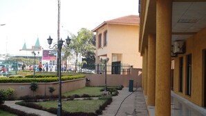 A courtyard with a paved walkway, trimmed hedges, and a building with a tiled roof. - Bridgeview Hotel & Conference Centre (Lilongwe)