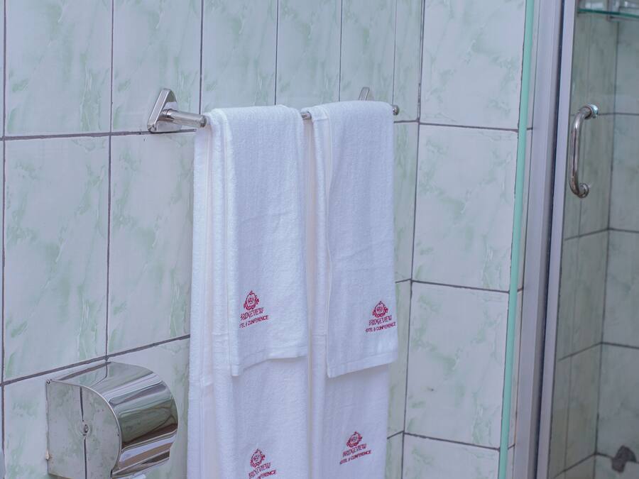 A bathroom with two white towels hanging on a rack, a towel dispenser, and a glass shower enclosure.