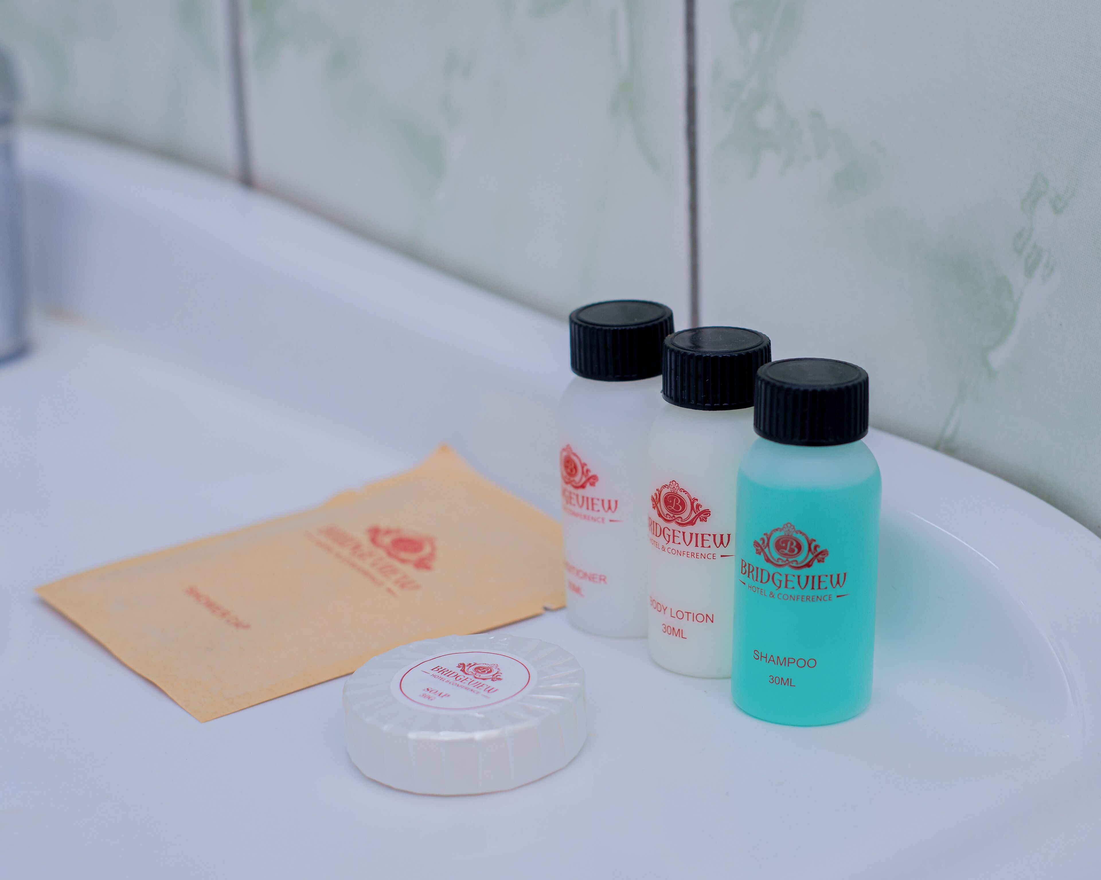 A bathroom counter with toiletries including body lotion, shampoo, and a tissue.