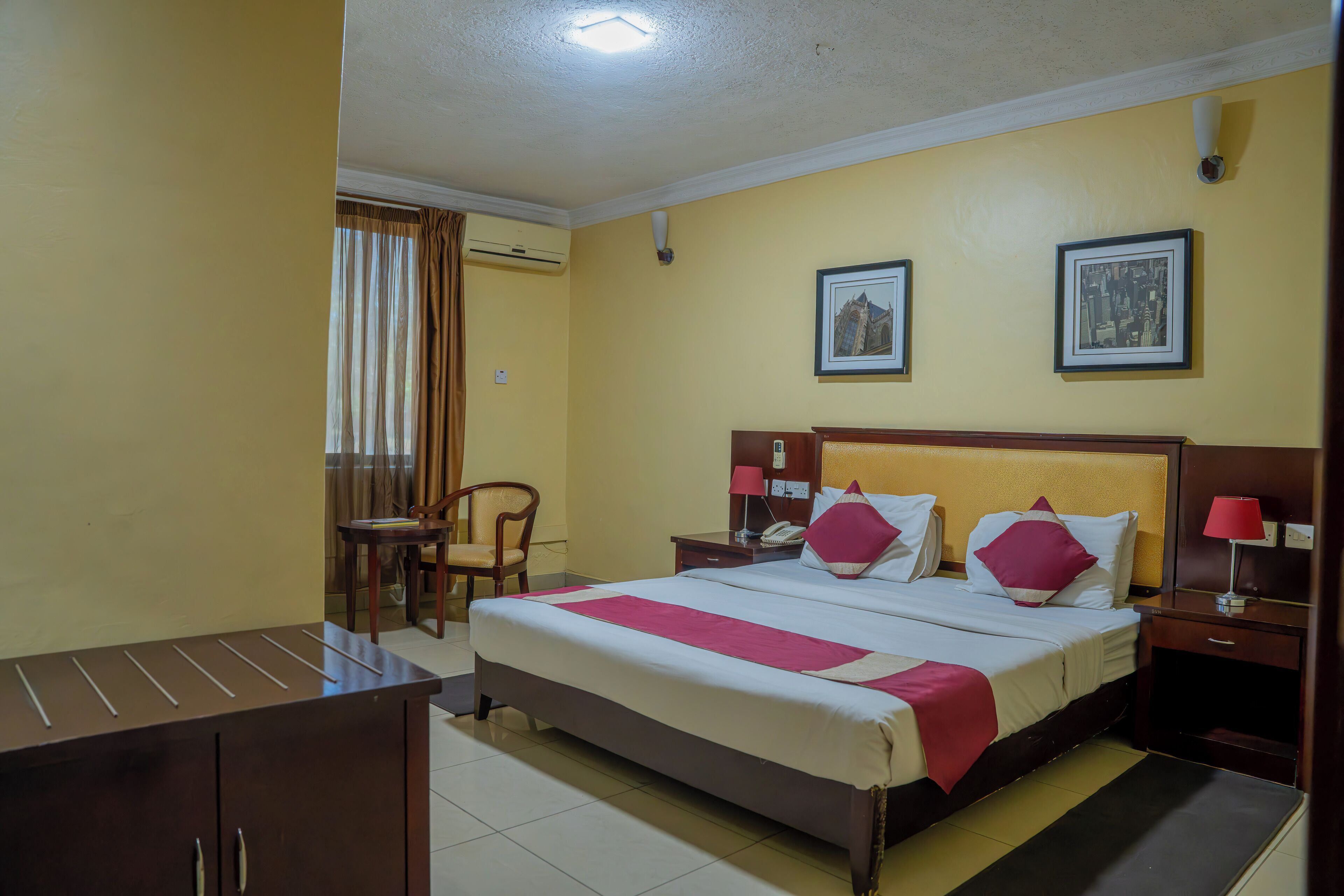 A hotel room with a bed, bedside tables, a desk, and a chair.