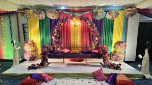 A stage with a sofa and floral decorations, surrounded by draped curtains and colorful lighting. - Bridgeview Hotel & Conference Centre (Lilongwe)
