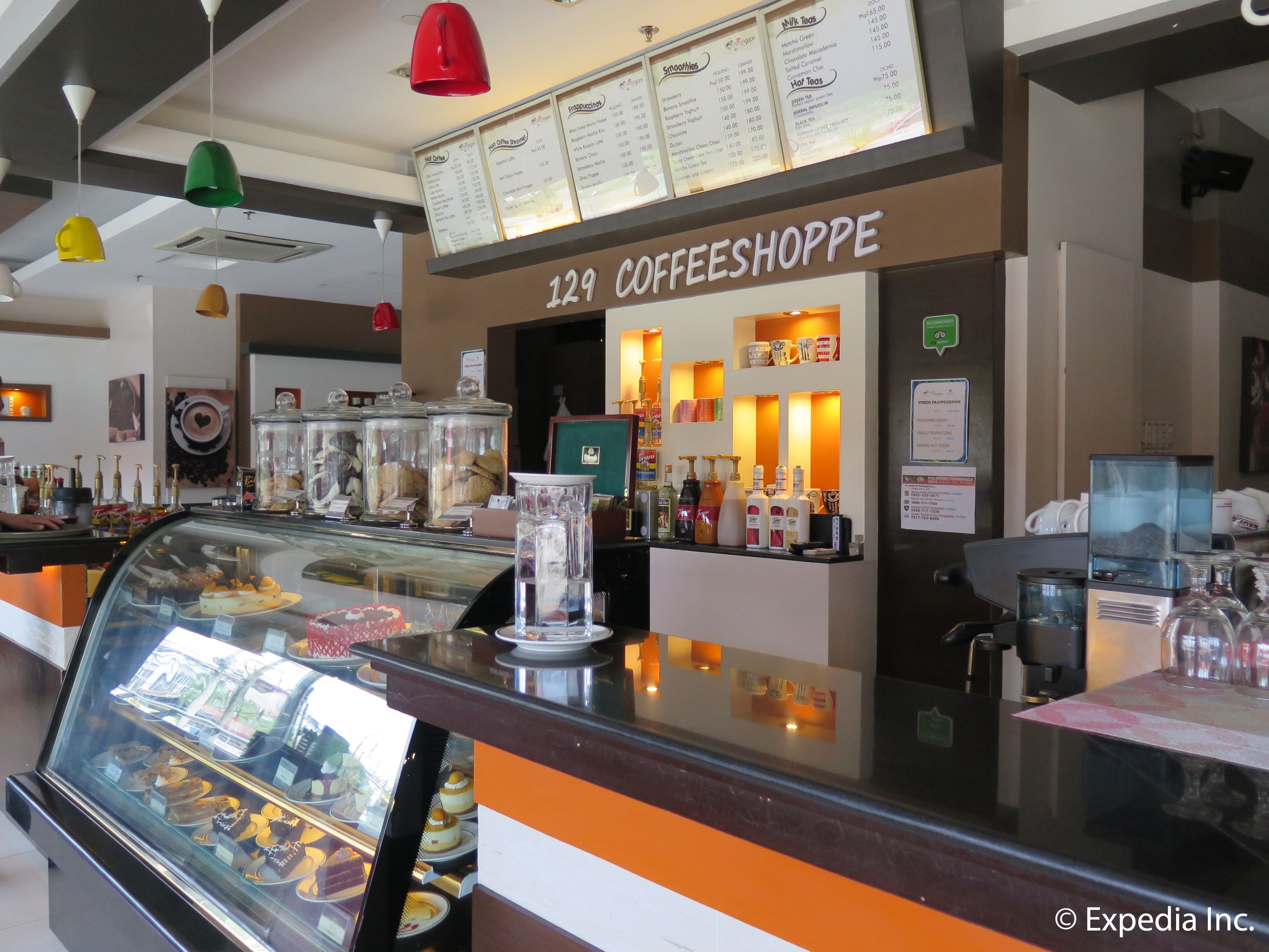 Ein Café-Interieur mit einer Glastheke voller Gebäck und einer Speisekarte über der Theke.