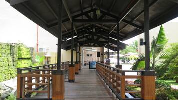 A covered walkway with wooden railings and a tiled floor, leading to a building entrance.