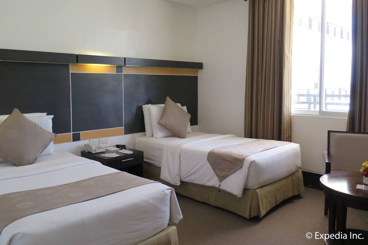 A hotel room with two beds, a desk, and a chair.