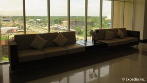 A modern living room with a large window, a beige sofa, and a small table with a vase.