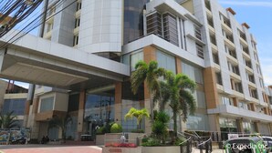 A modern multi-story building with a glass facade, outdoor seating area, and a covered entrance.