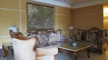 A traditional room with ornate furniture, a large framed painting, and a chandelier.