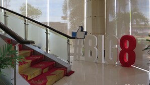 A modern interior with a staircase leading to a balcony, large letters spelling "BIG8", and a glass railing.