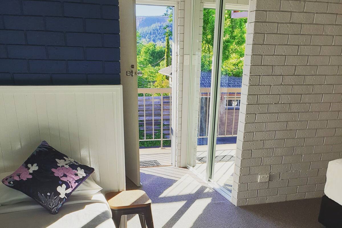 Una habitación con una cama, una silla y vistas a un balcón con cerramiento de madera.