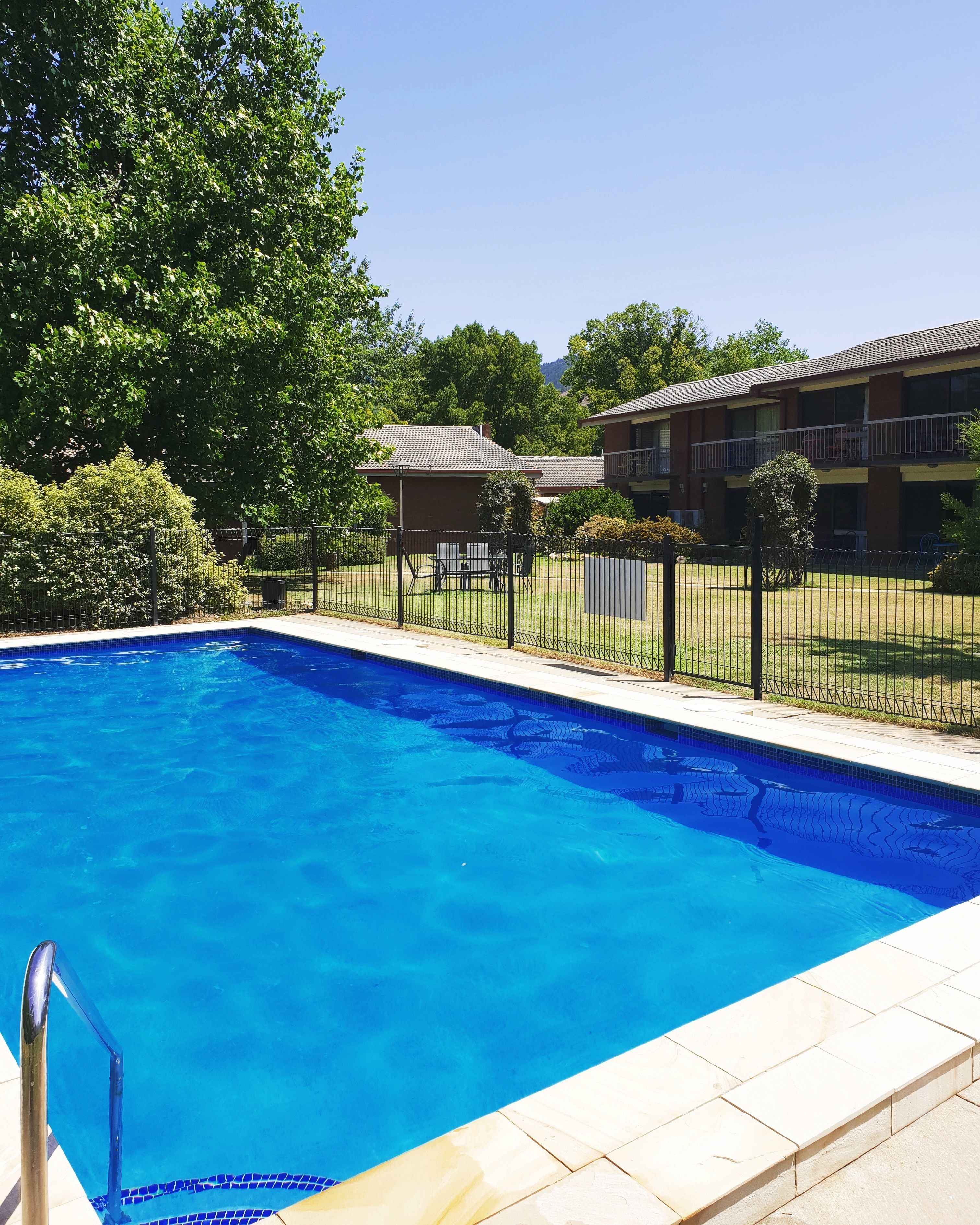 Una piscina rectangular con agua azul cristalina, rodeada por una solana con baldosas.