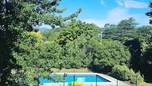 A backyard with a swimming pool, surrounded by trees and a grassy lawn. - Motel Sierra (Bright)