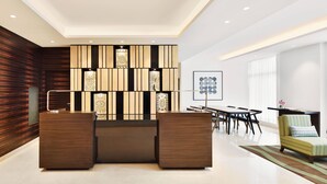 A modern reception area with a wooden panel wall, a reception desk, and a seating area with a sofa and chairs. - Fairfield by Marriott Pune Kharadi (Pune)