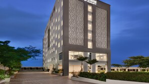 A modern hotel with a facade featuring geometric patterns, large windows, and a well-lit entrance. - Fairfield by Marriott Pune Kharadi (Pune)