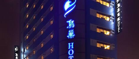 A tall hotel building with a prominent blue neon sign for the NEST HOTEL.
