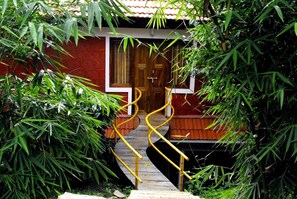A wooden staircase leading to a red door, surrounded by lush green foliage. - Crescent Residency (Sulthan Bathery)