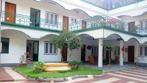 A courtyard with a central garden, multiple balconies, and a seating area. - Raja Park Beach Resort (Varkala)
