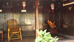 A wooden interior with a wicker chair and a statue. - Raja Park Beach Resort (Varkala)