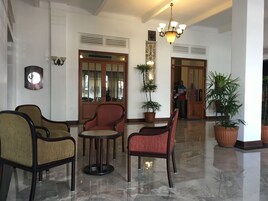 Un vestíbulo con candelabro, plantas en macetas y una puerta de madera.
