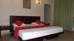 A hotel room with a large bed, two bedside tables, a nightstand, a framed picture on the wall, and a green curtain. - Shalimar Hotel (Colombo)