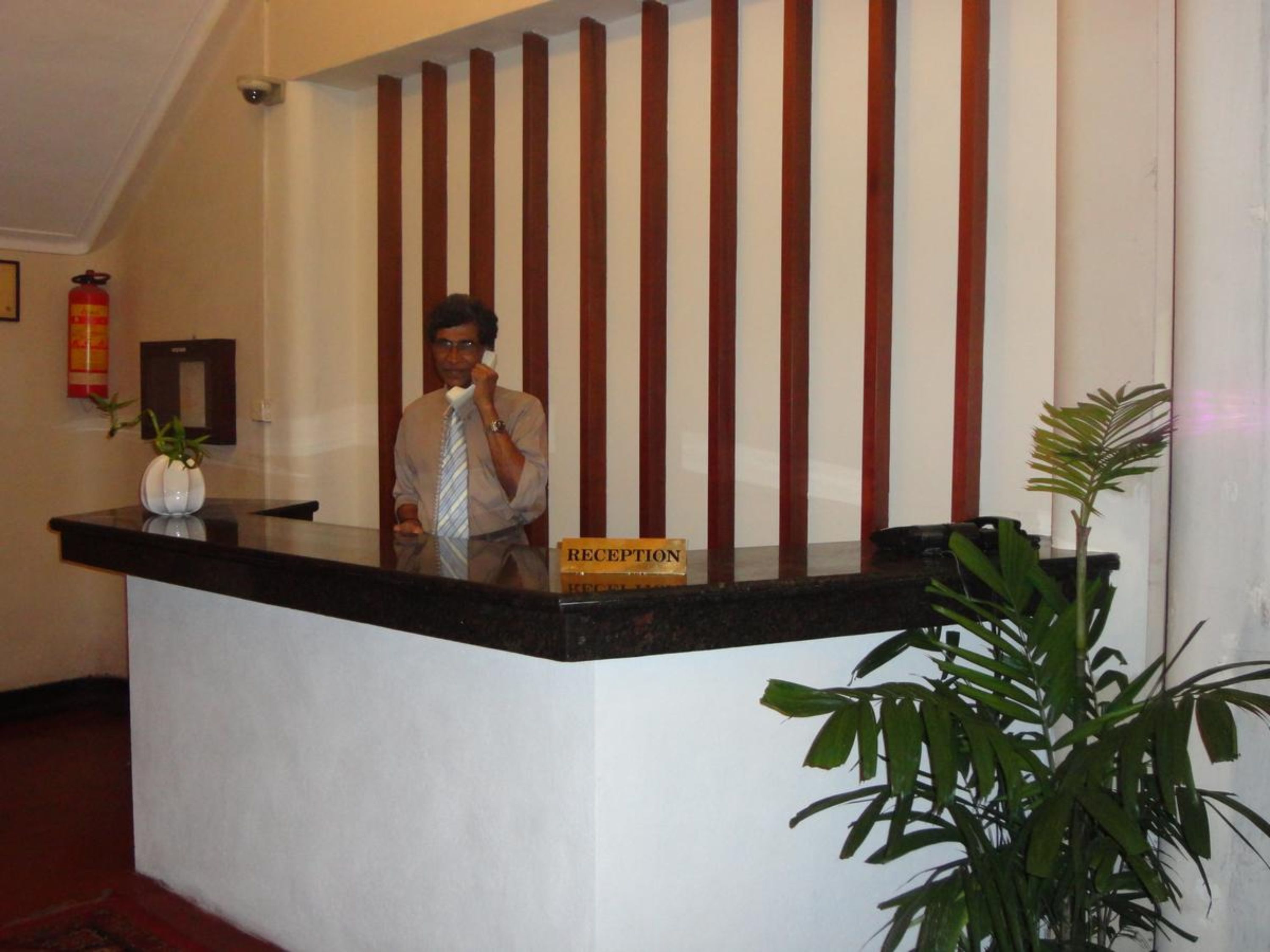 Un mostrador de recepción con un cartel que dice "RECEPTION" y un hombre detrás.