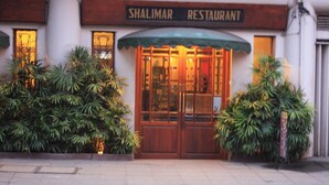The exterior of Shalimar Restaurant with a traditional wooden facade, large glass windows, and a green awning. - Shalimar Hotel (Colombo)