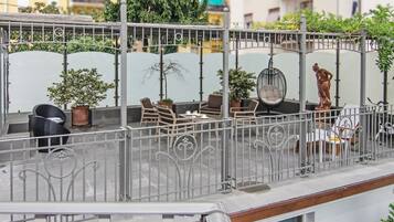 A rooftop terrace with outdoor seating, potted plants, and a statue.