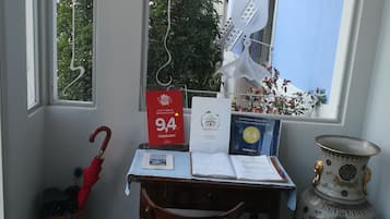 A room with a window, a desk with papers, a vase, and a chair.