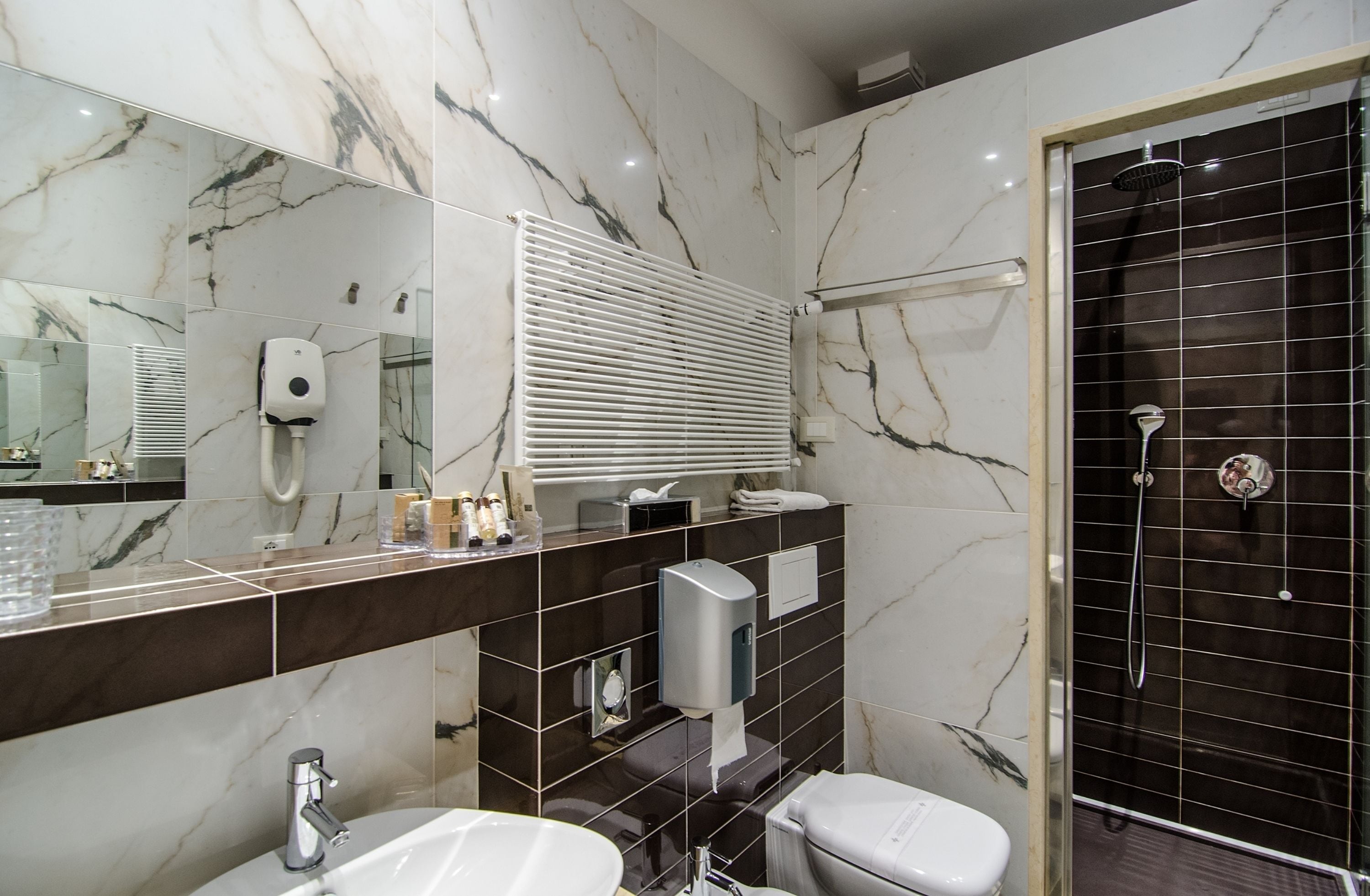 Une salle de bain moderne avec un meuble-lavabo en marbre, un grand miroir, des toilettes et un espace douche.