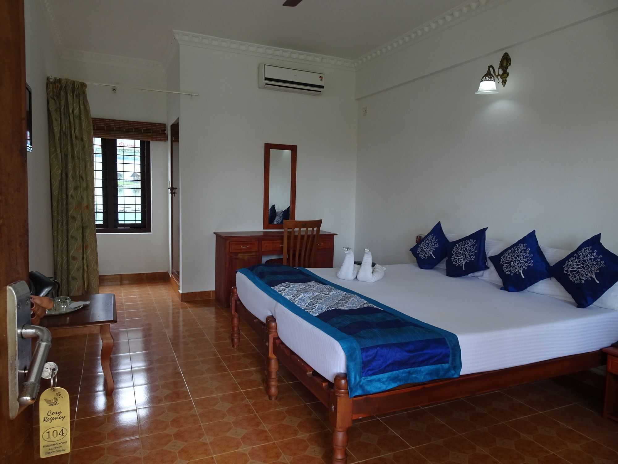 A bedroom with a bed, a dresser, a mirror, and a window.