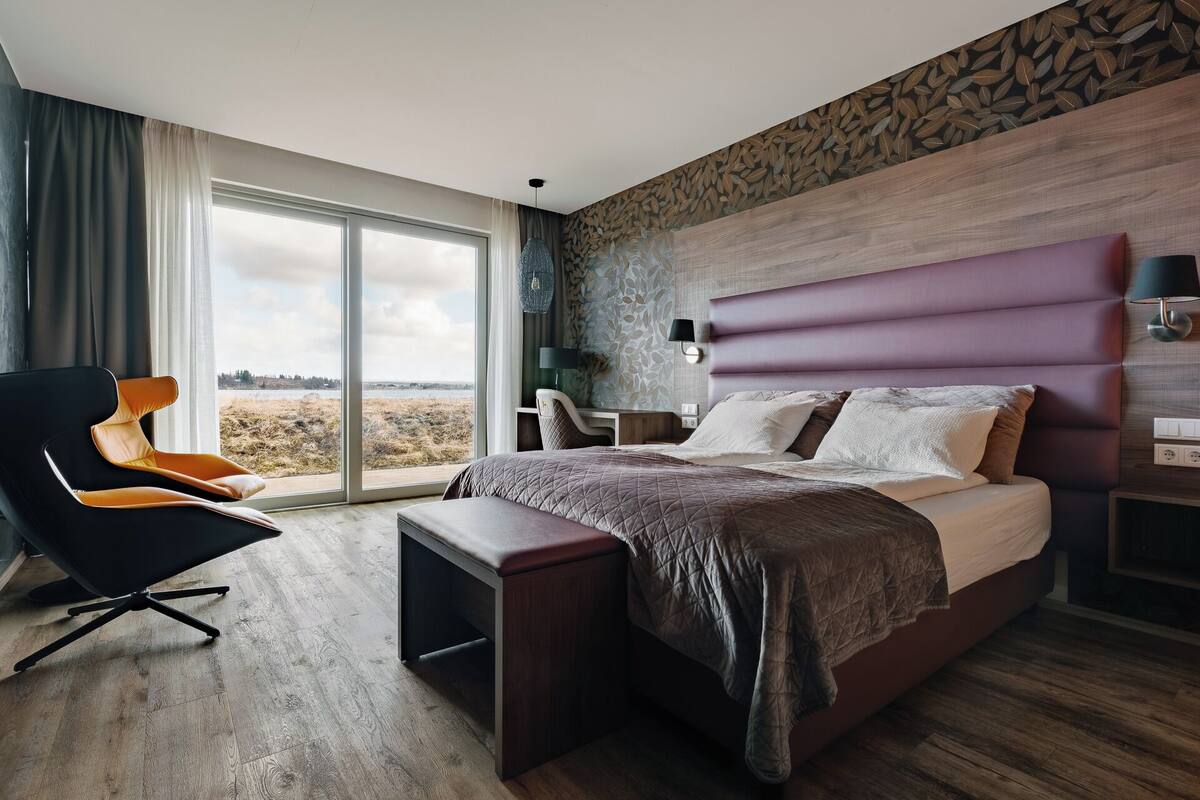 Et moderne hotelværelse med en stor seng, et skrivebord, en stol og udsigt til det fri.