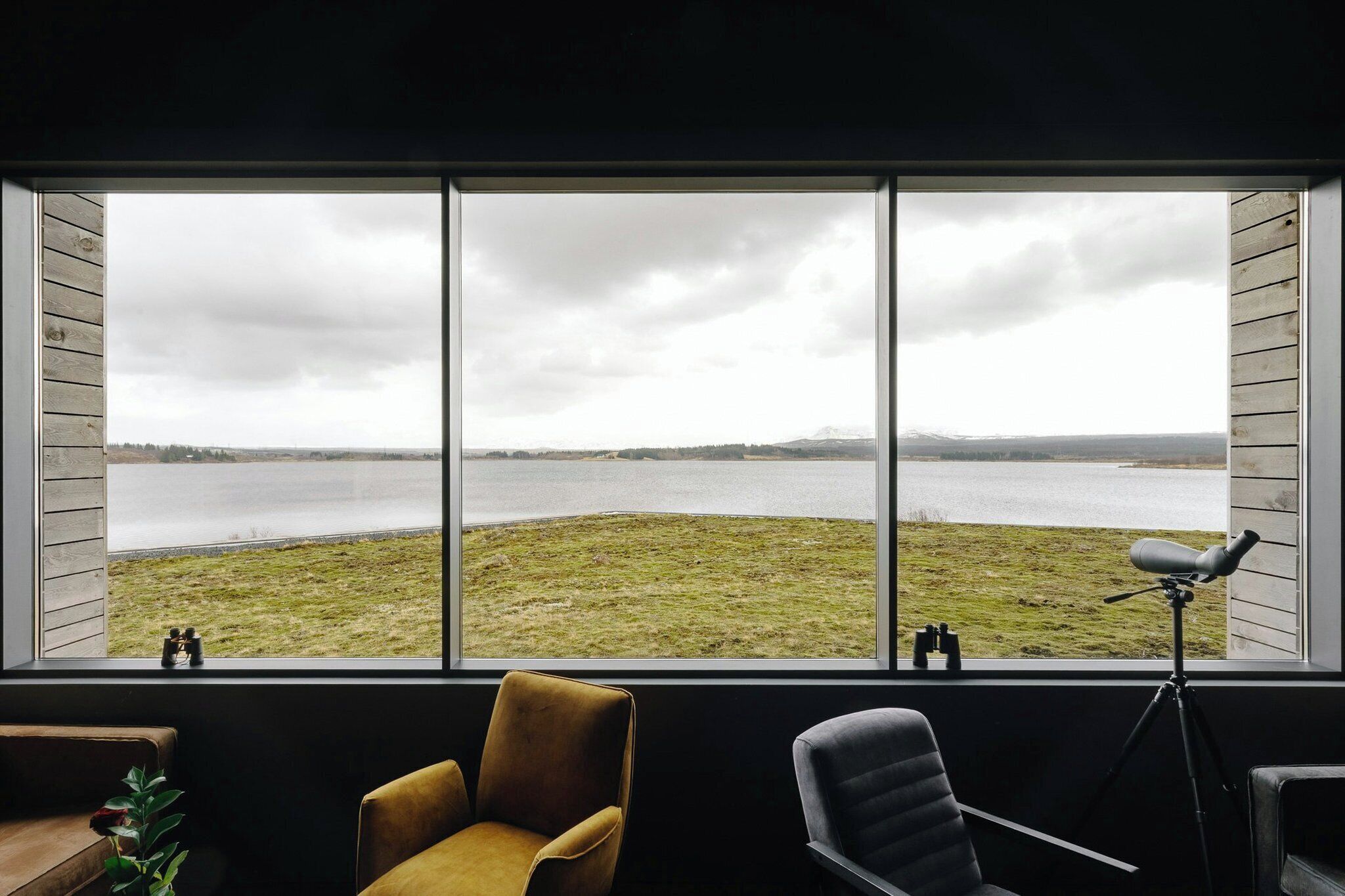 Habitación con ventana grande que ofrece vistas a un lago y zona verde.